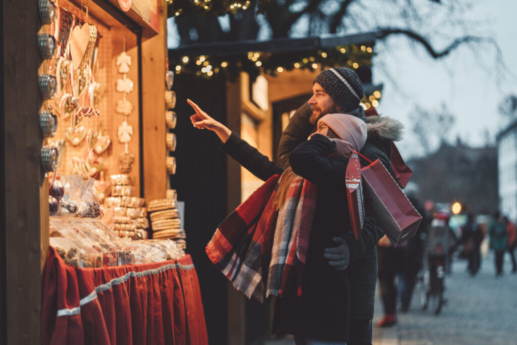 Happy smiling young couple shopping at Christmas market.