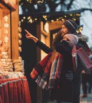 Happy smiling young couple shopping at Christmas market.